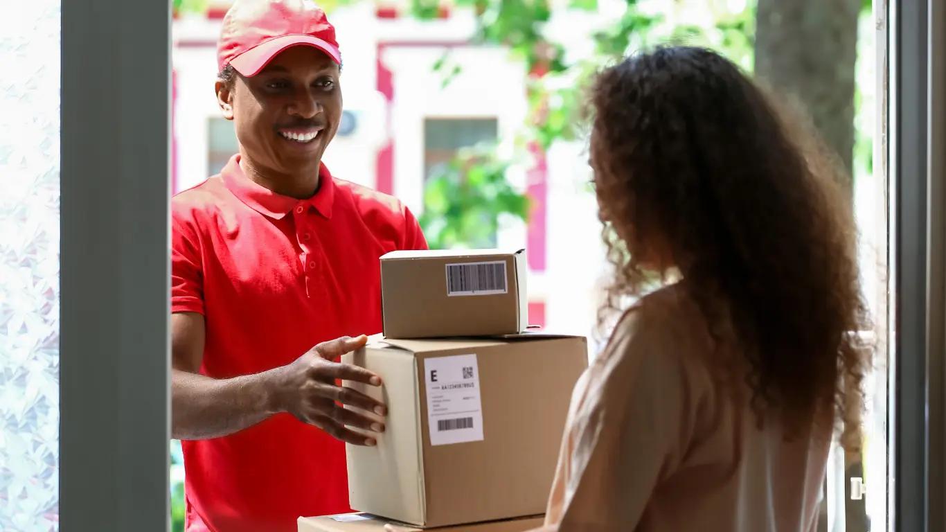 Entregador a entregar um pacote numa casa para uma senhora