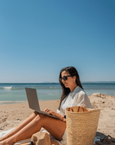 Photo d'une femme qui travaille sur son ordinateur à la plage.