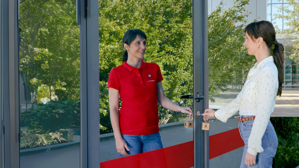 Photo d'une femme qui entre entre dans un magasin. Elle voit son reflet dans la porte vitrée et cela symbolise le début de son projet entrepreneurial.